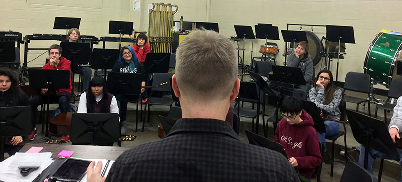 Bob Habersat lectures his 2nd period Guitar class in the Band room. As his students practice playing a new piece of music, he gives them one-on-one help when they struggle.
