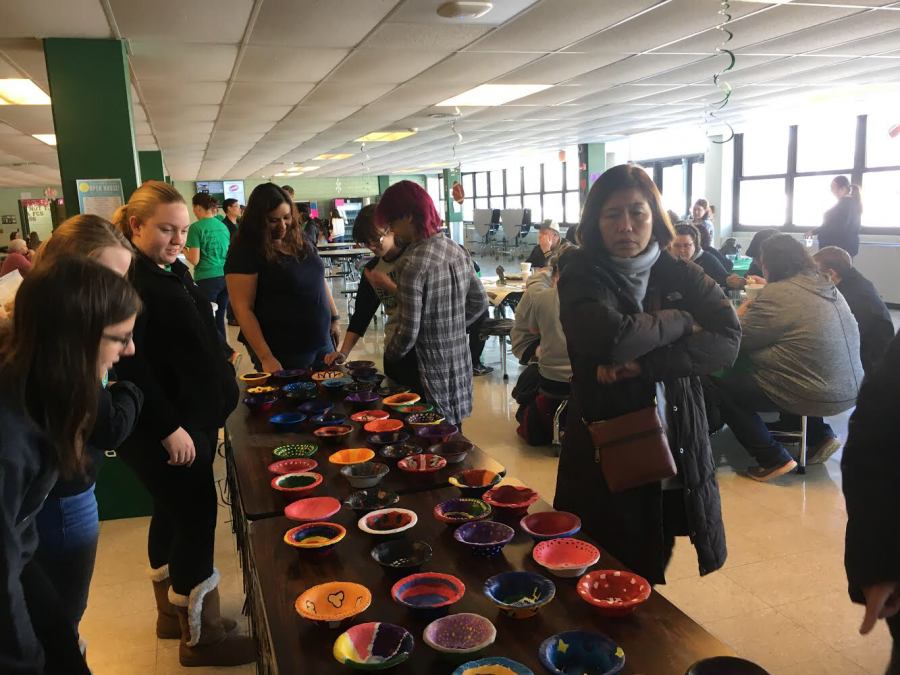 A group of fundraiser attendees surveys the handmade bowls for purchase