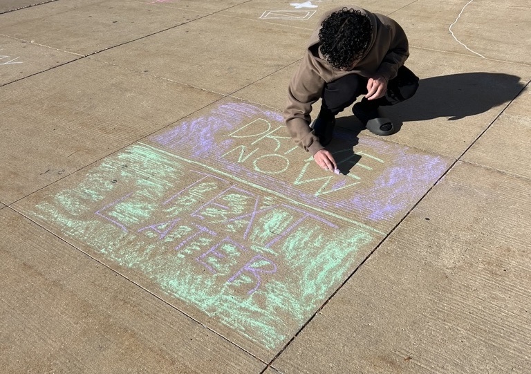 After school, members of SADD draw with chalk quotes and signs to spread awareness.